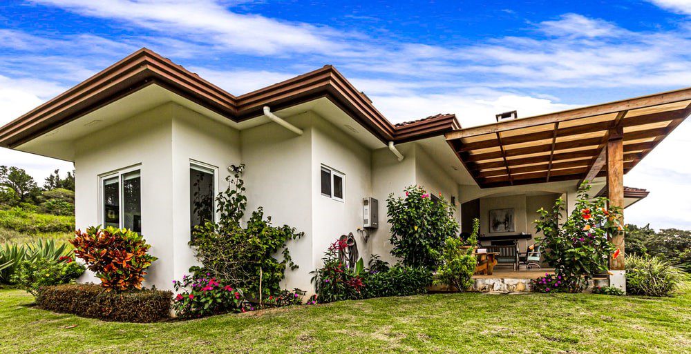 green plants outside a white and brown home landscaping and hardscaping