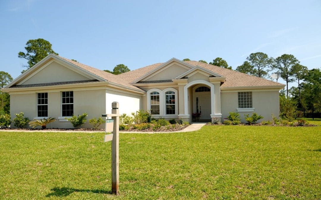 A white and brown concrete bungalow with an unattractive outdoor space.