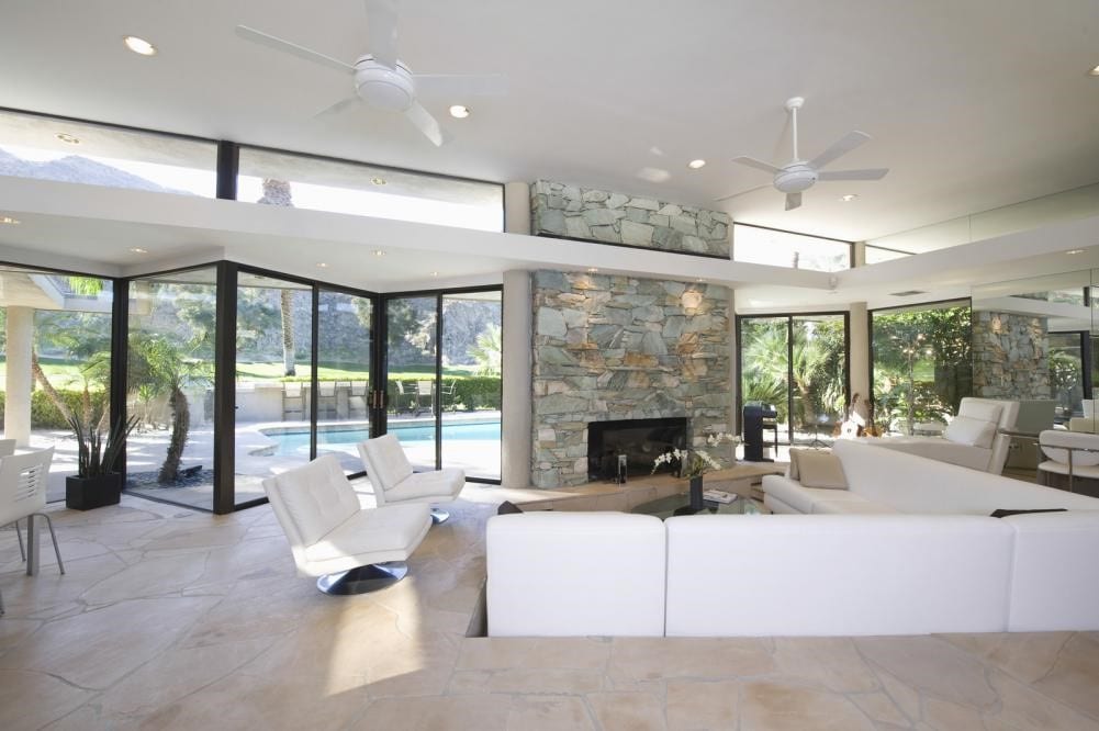 Seating area and stone fireplace in a modern, spacious living room with a pool view.