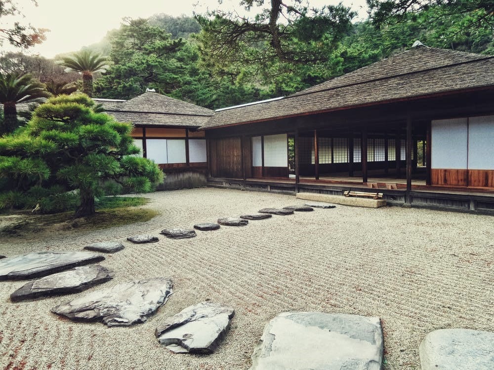 A beautiful walkway made with gray gravel on a bed of pebble stones leading to the house entrance. 