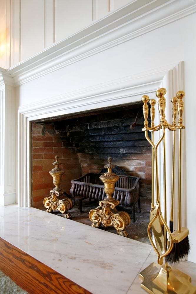 Old wood fireplace with white mantel and antique inserts.