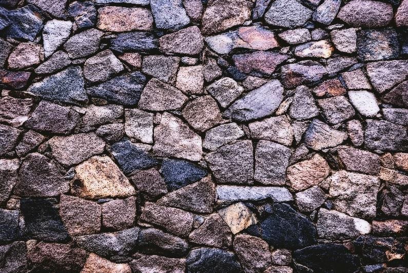 A wall made up of black and brown stones.