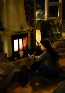 A woman sitting next to a fireplace.