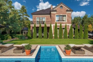 Neatly trimmed trees behind a house with a pool