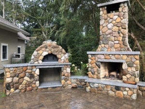 Two stonework fireplaces installed in a backyard