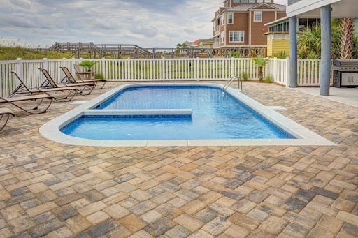 A pool patio using multiple variations of stone, including pavers