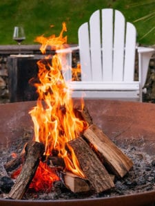An Outdoor fire pit on a stone patio with adirondack chairs in Maine.jpeg