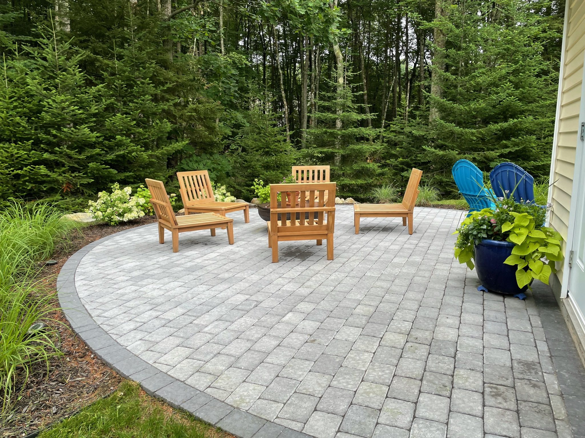 curved paver patio with fire pit Adirondack chairs