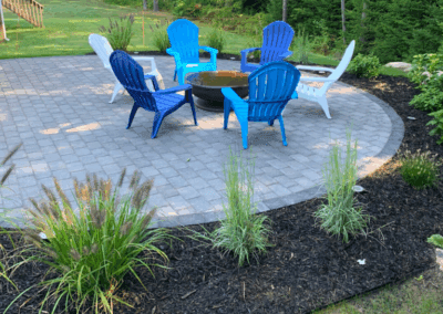 circular-paver-patio-fire-pit-colorful-adirondack-chairs-landscaping.