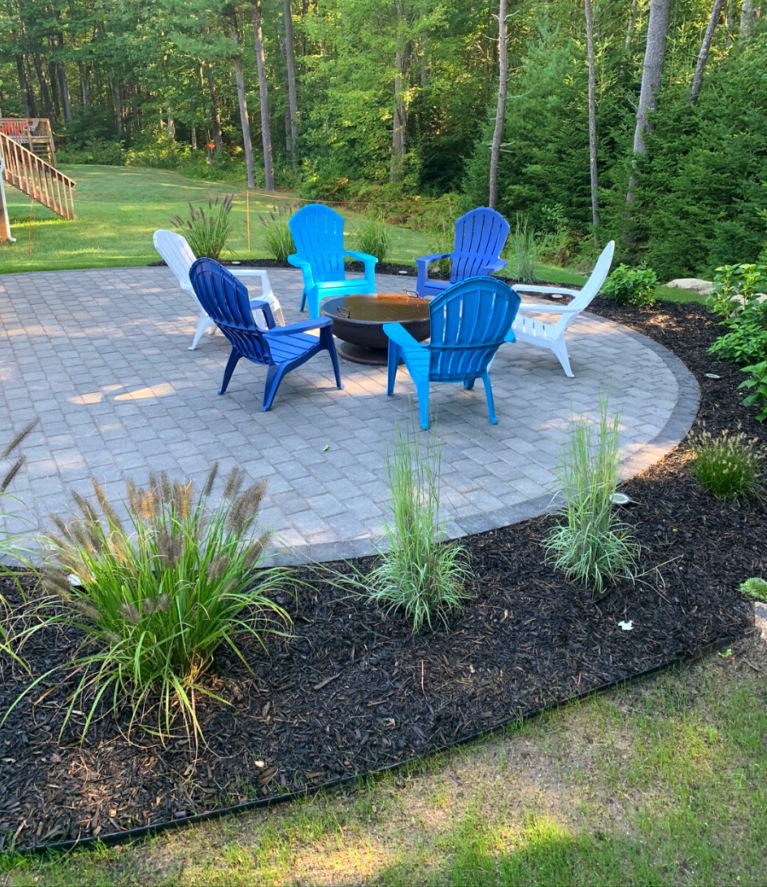 circular-paver-patio-fire-pit-colorful-adirondack-chairs-landscaping.