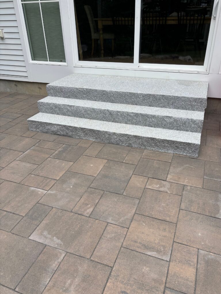 Three-tier granite steps leading to sliding glass doors on a Pownal, Maine patio