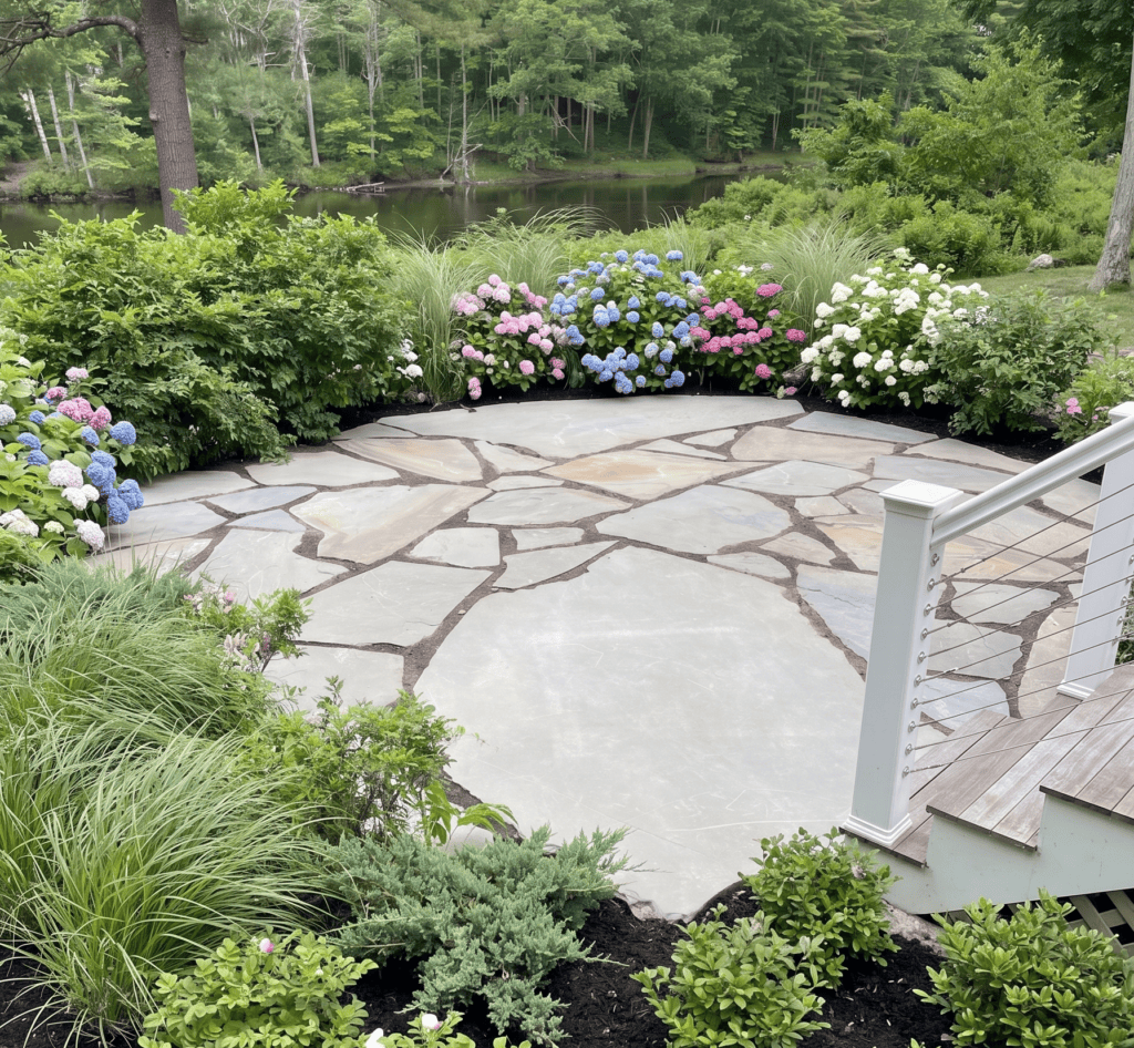 Flagstone patio bordered by colorful hydrangeas and ornamental grasses, overlooking the water in Yarmouth, Maine